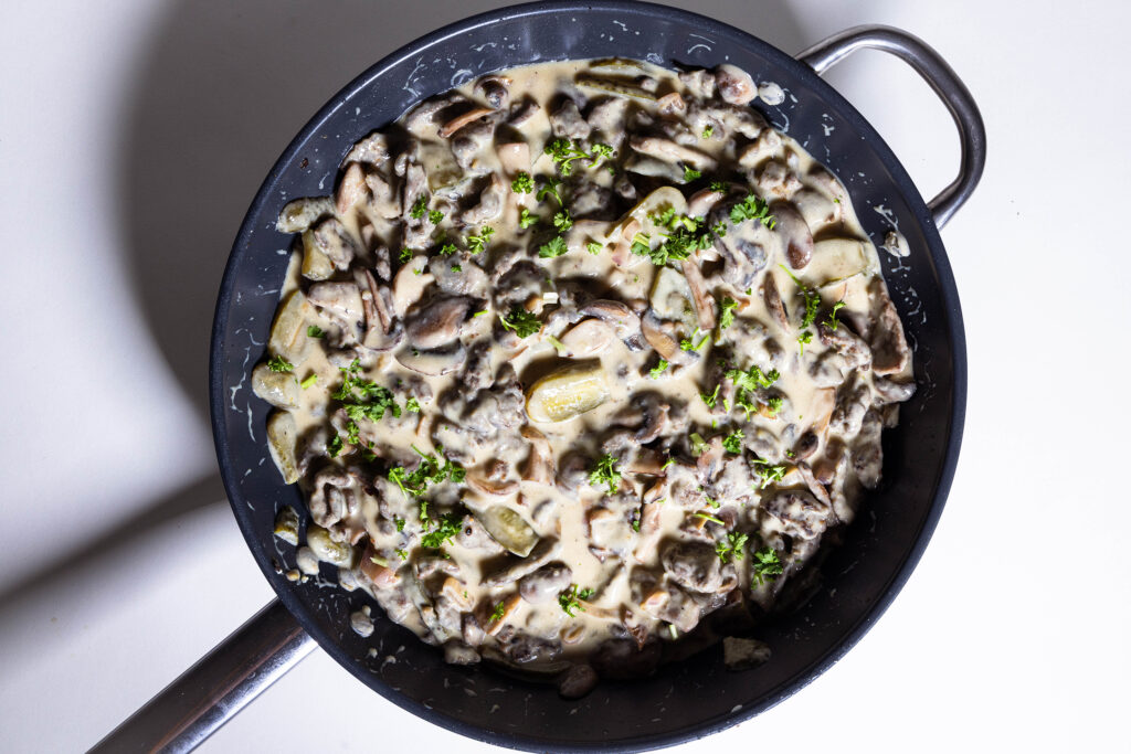 Veganes Boeff Stroganoff in einer Pfanne, mit Petersilie bestreut.