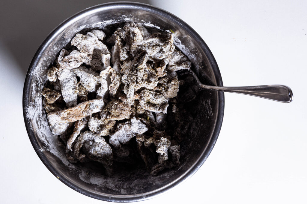 Veganes Sojafleisch wird in Mehl gewendet.