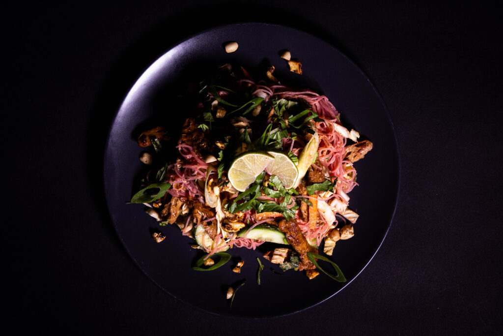 Pinker Glasnudelsalat mit Teriyake Seitan auf einem Teller.