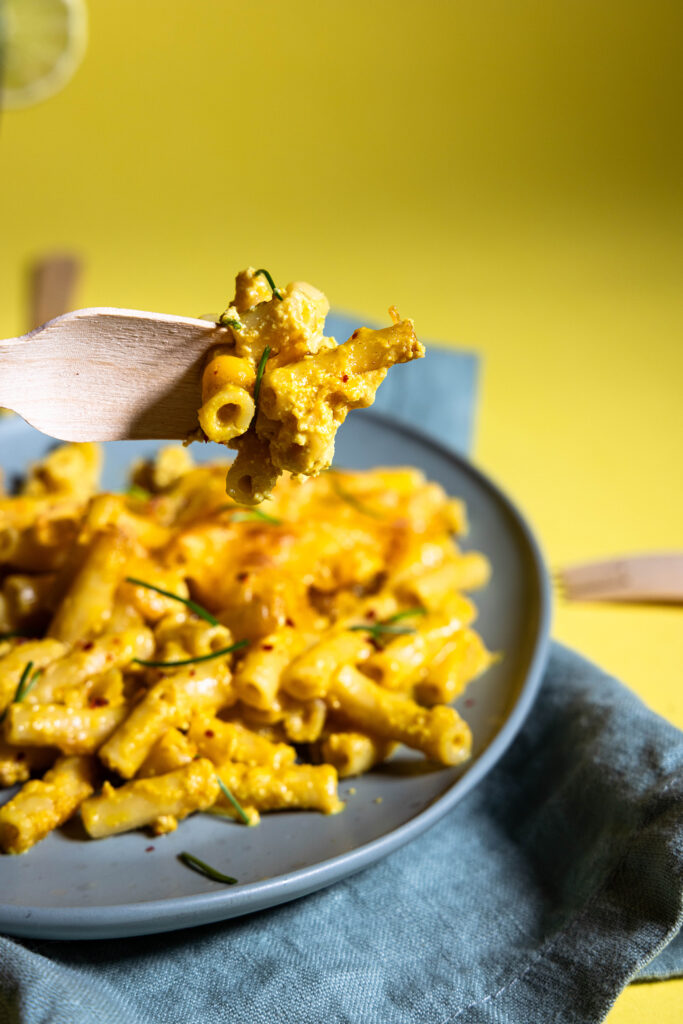 Vegane Maccaroni and Cheese auf einer Gabel und auf einem Teller