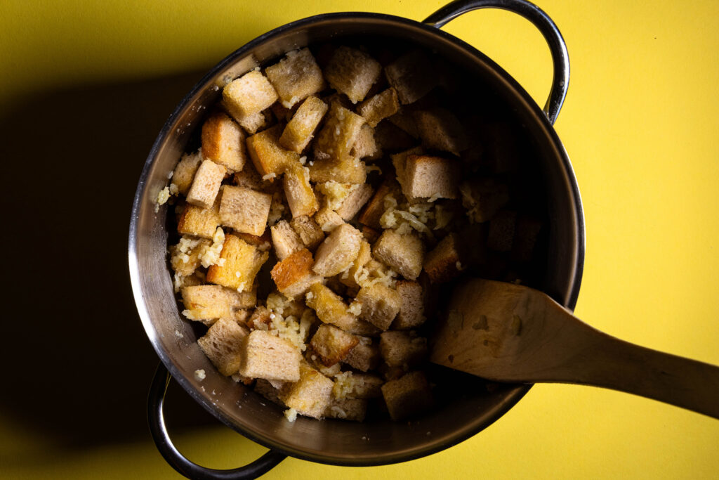 Knoblauch und Brot werden in heißem Olivenöl unter Rühren in einem großen Topf angebraten.