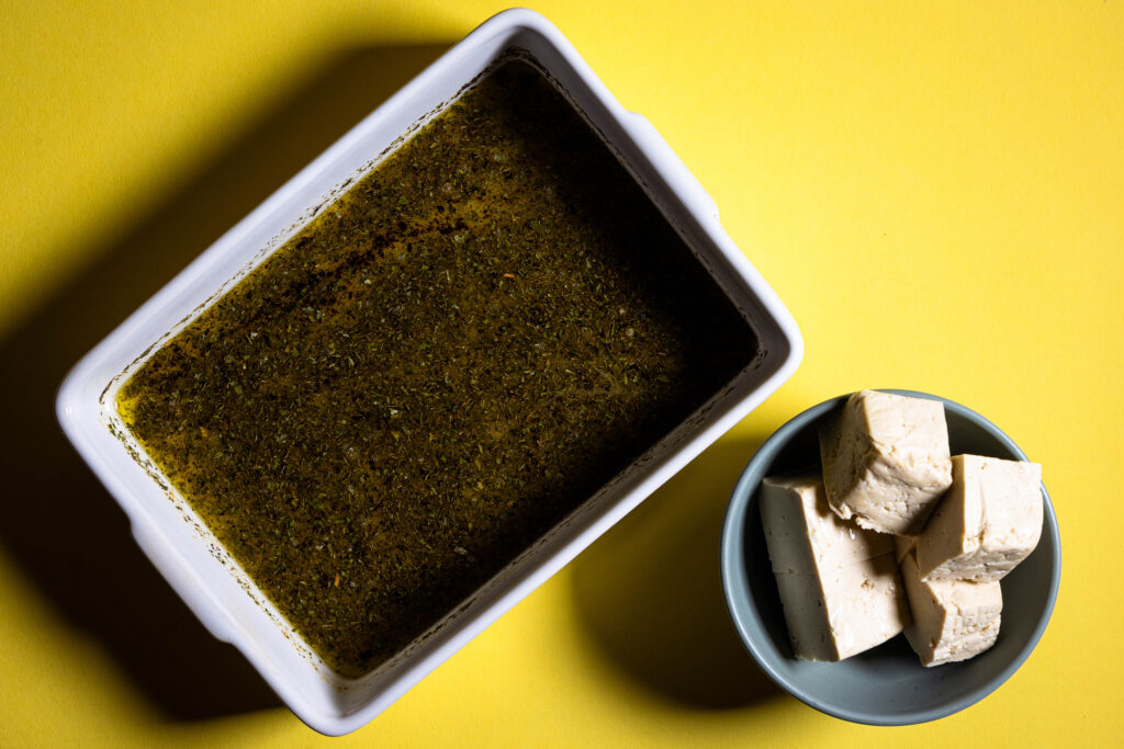 Eine Schale mit Marinade und eine mit Tofuwürfeln.