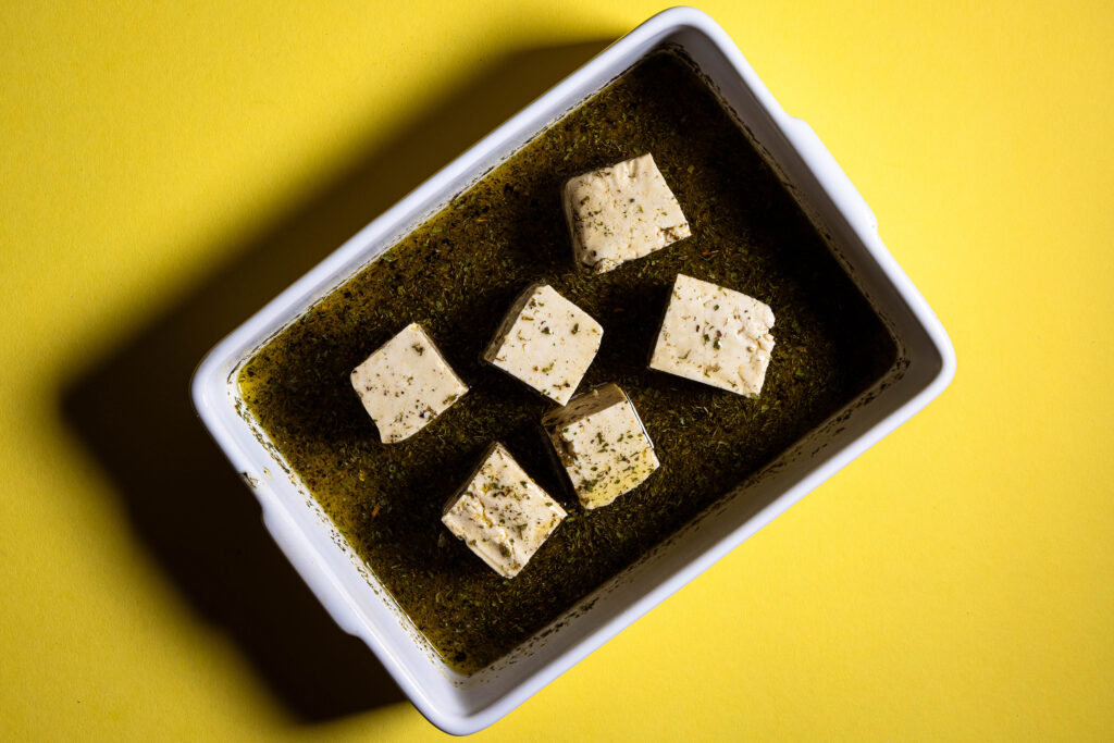 Tofuwürfel in Marinade in einer kleinen Auflaufform.