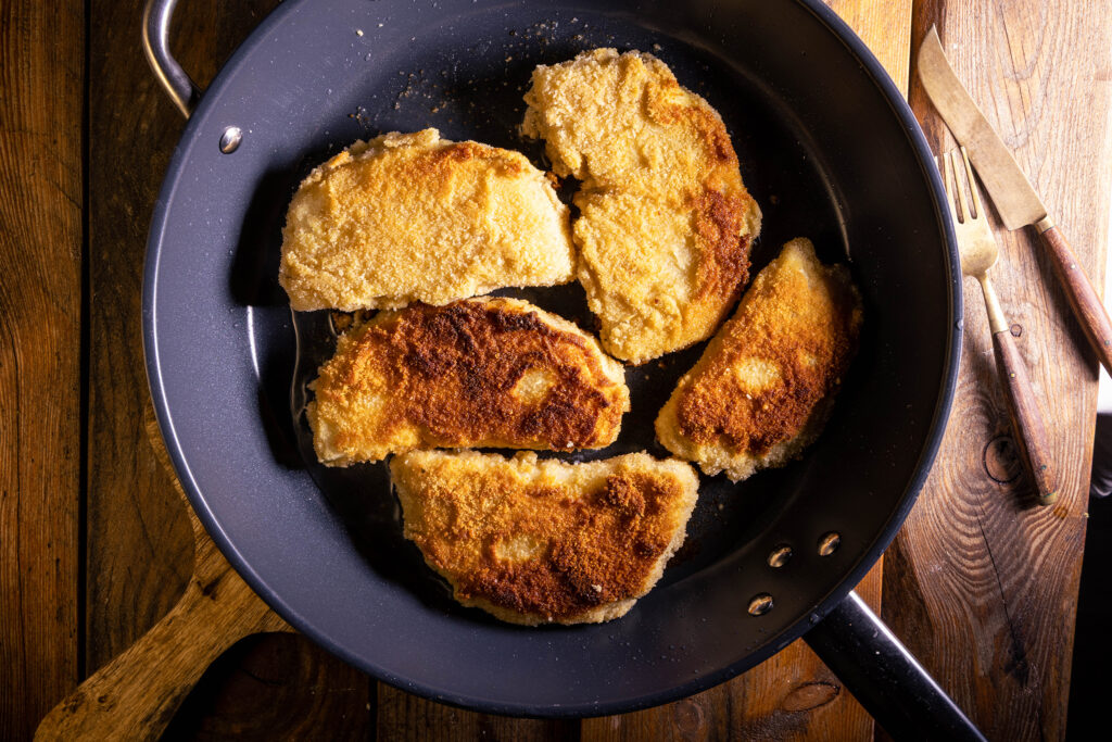 Sellerieschnitzel braten in einer Pfanne.
