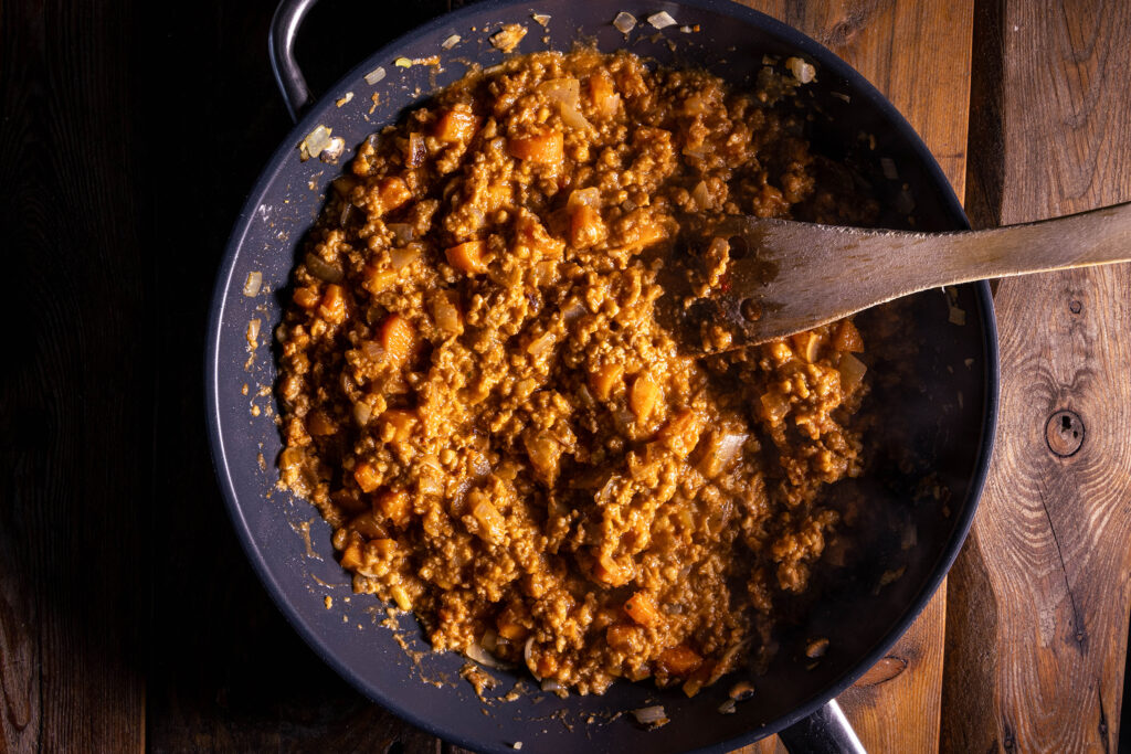 Eine vegane Fleischfüllung wird in einer Pfanne zubereitet.