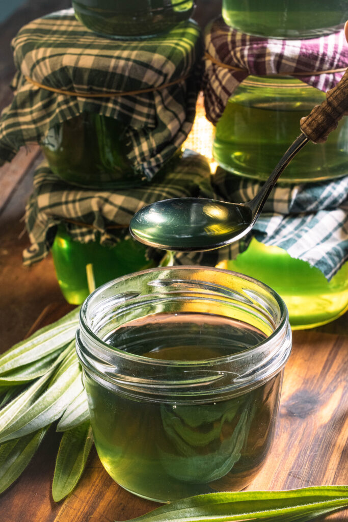 Spitzwegerichsirup in Gläsern und auf einem Löffel
