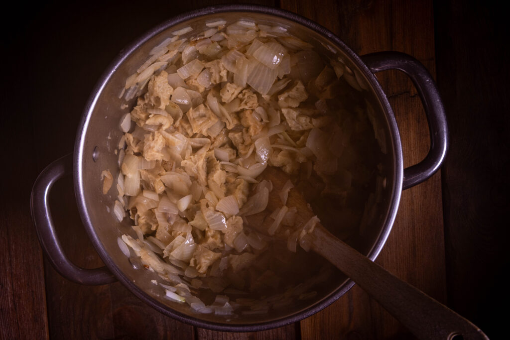 Sobald die Zwiebeln glasig sind auch das Seitanfleisch mit anbraten.
