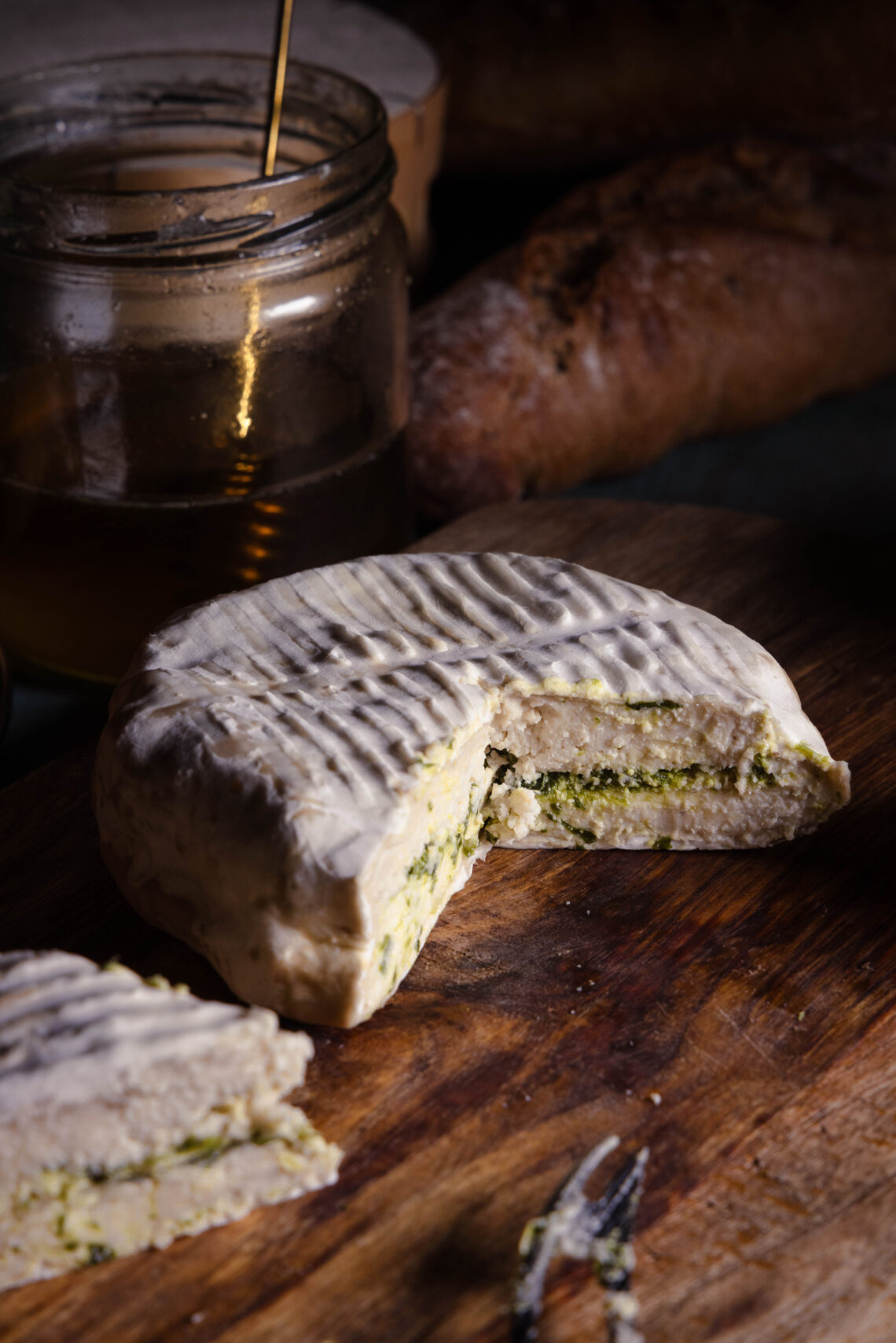 Mit Bärlauch durchzogener veganer Camembert angeschnitten auf einem Holzbrett