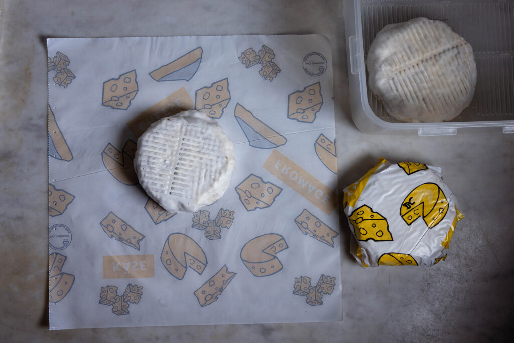 Vegane Camemberts mit Bärlauch werden in Käsepapier verpackt.