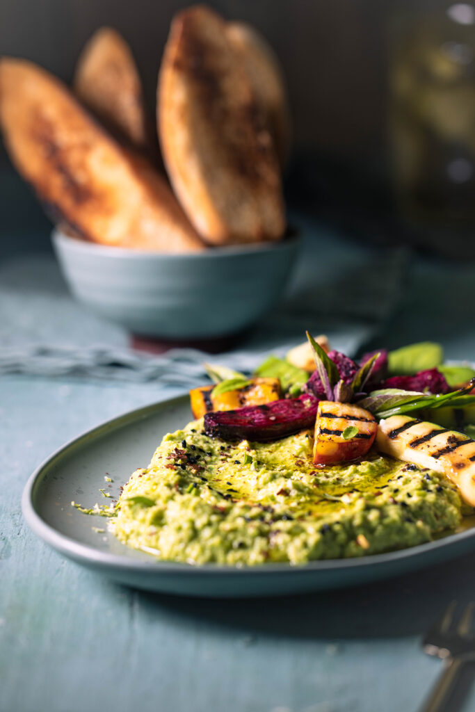 Grüner Umami Dip mit Grillgemüse auf einem Teller. Dahinter: geröstetes Brot.