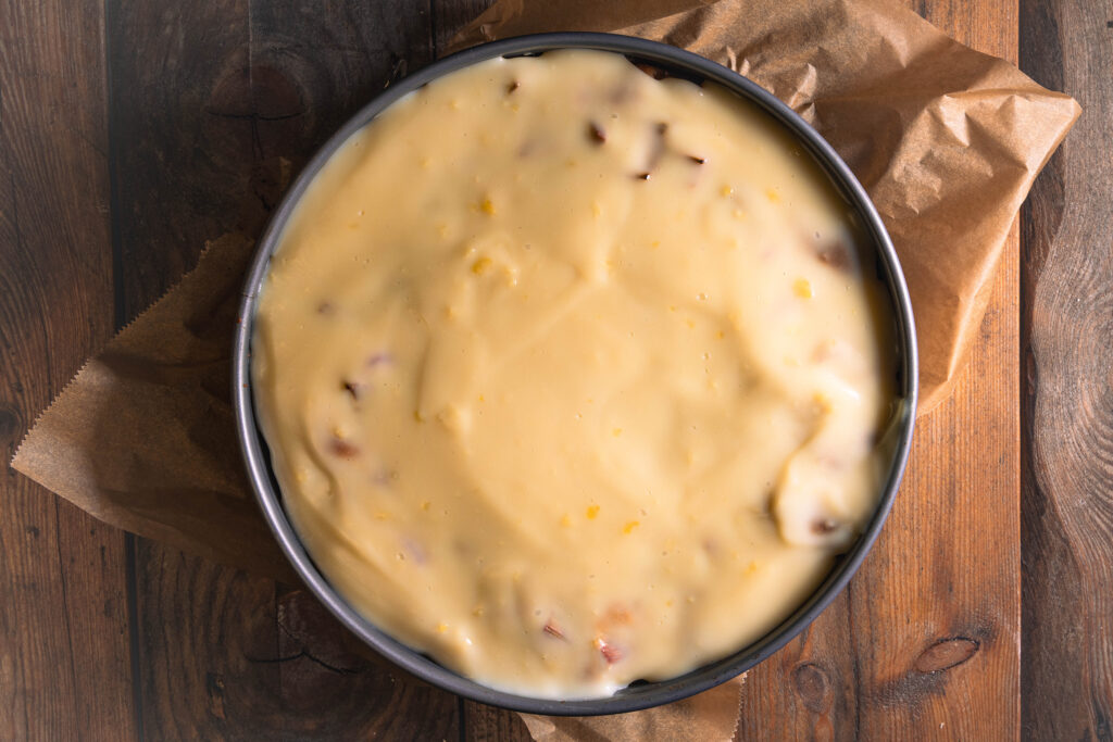 Eine frisch aufgetragene Puddingschicht auf einem Rhabarberkuchen.