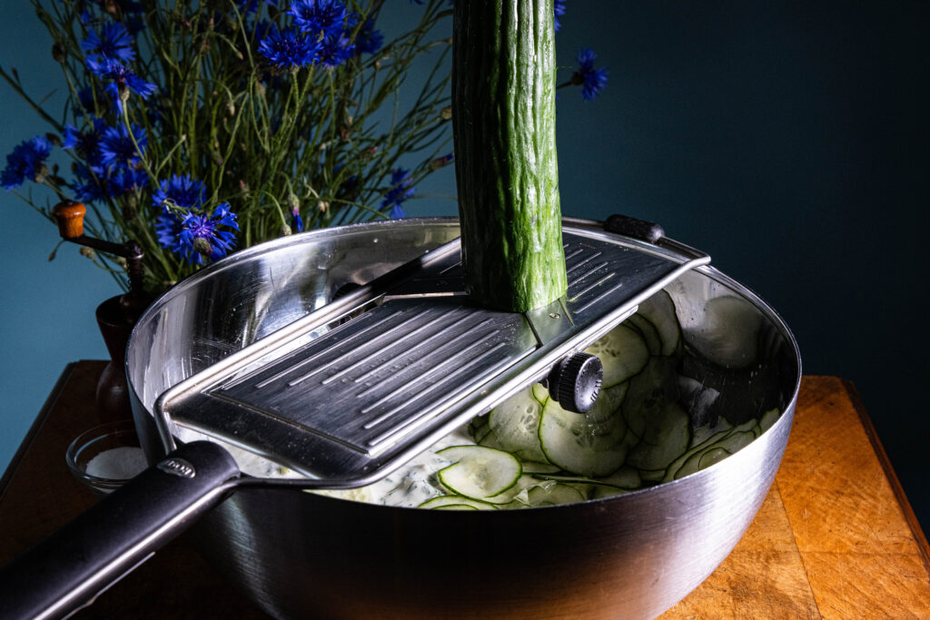 Eine Gruke wird in eine Schale mit Gurkensuppe gerieben.